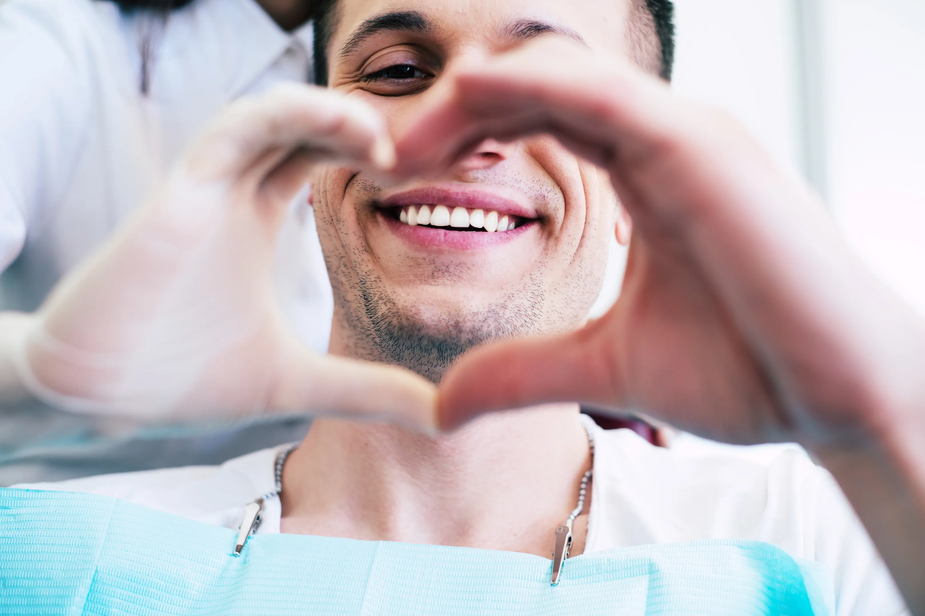 Happy patient framing their healthy smile with their hands