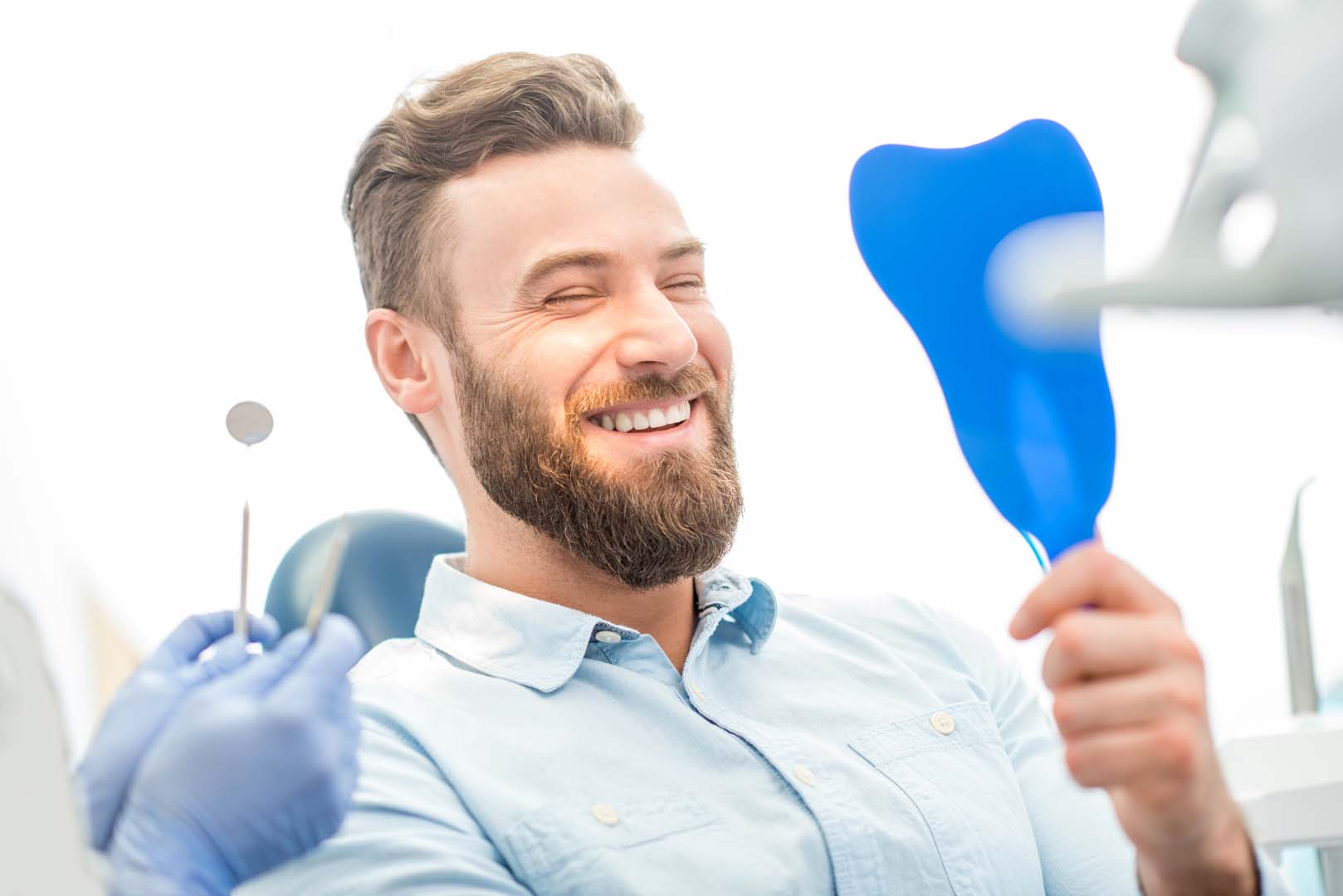 Happy patient admiring their smile in a mirror at Glassell Dental