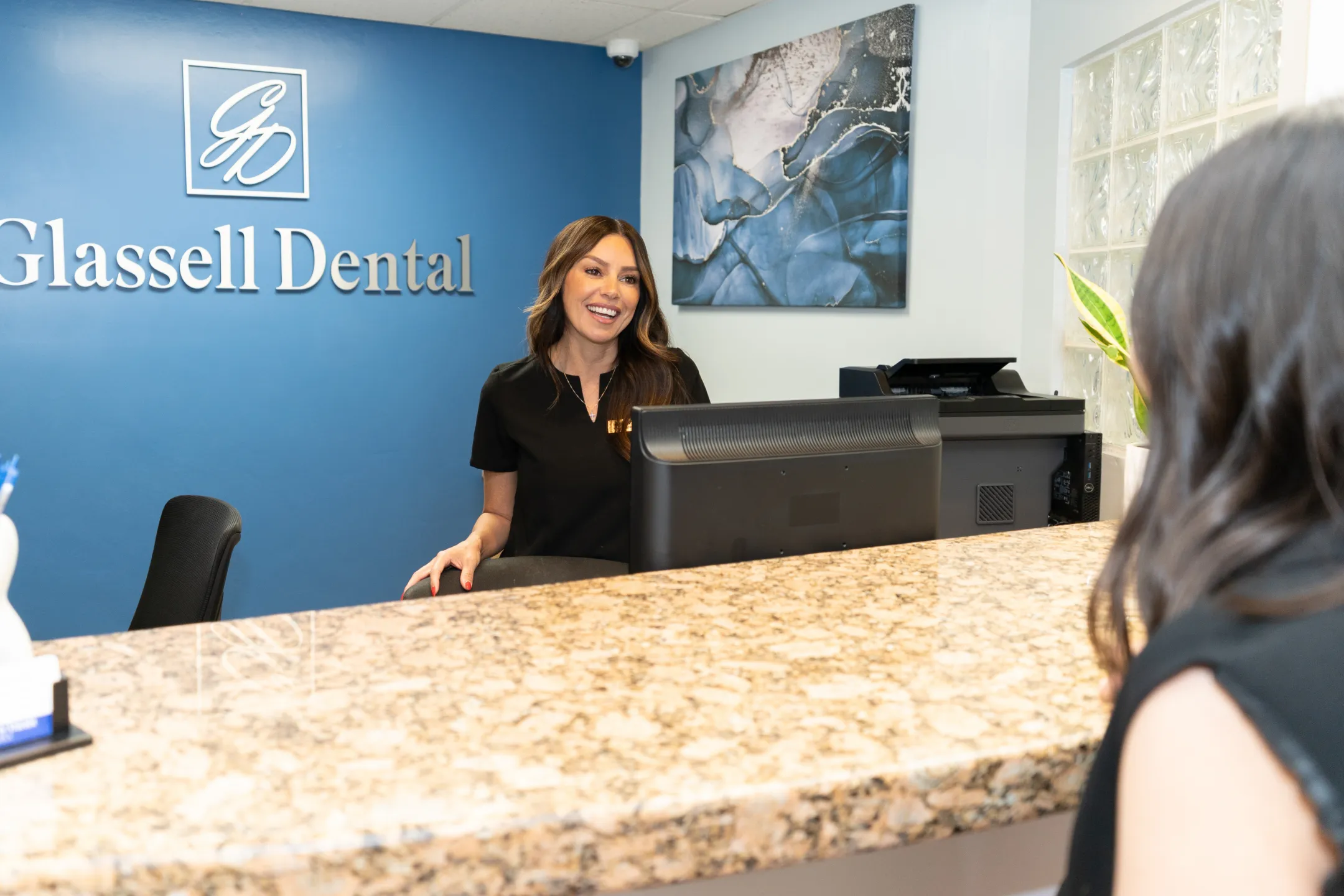 Glassell Dental front-office team helping a patient with intake forms